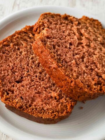 Zwei saftige Scheiben veganer Rührkuchen mit Apfelmus auf einem weißen Teller.